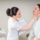 Dermatologist examining a female patient's skin closely during a consultation in a clinical setting.