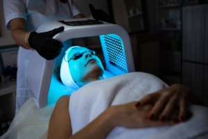 A client undergoing a professional LED light therapy facial treatment in a beauty clinic.